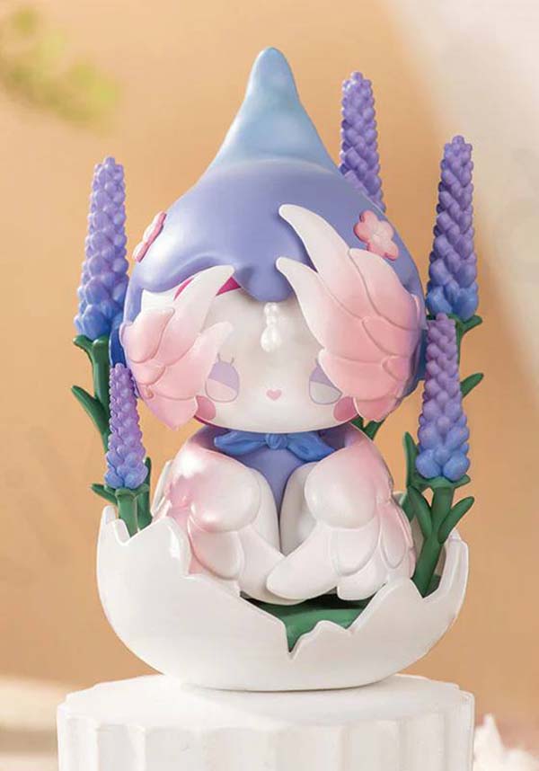 Cute figurine with pastel colors surrounded by purple flowers on a blurred background