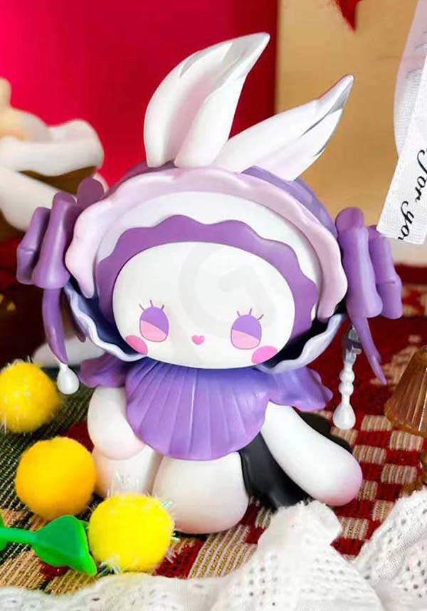 Plush toy with bunny ears and purple outfit on a textured surface