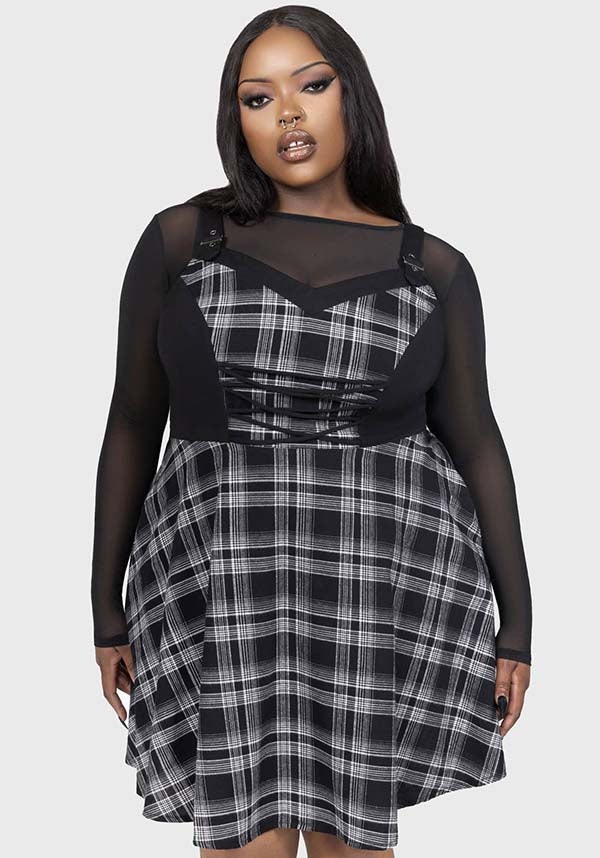 Plus size woman wearing a black and white plaid dress with sheer sleeves on a white background