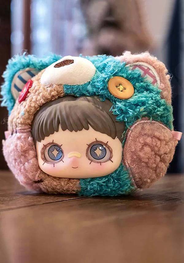 Plush toy with a character design wearing a colorful hat on a wooden surface.