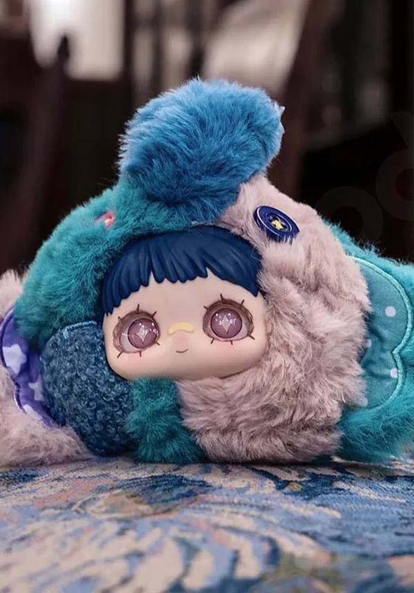 Plush toy with blue and gray outfit on a patterned surface