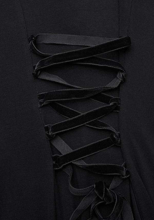 Close-up of a black dress with intricate lace-up detailing on a dark background