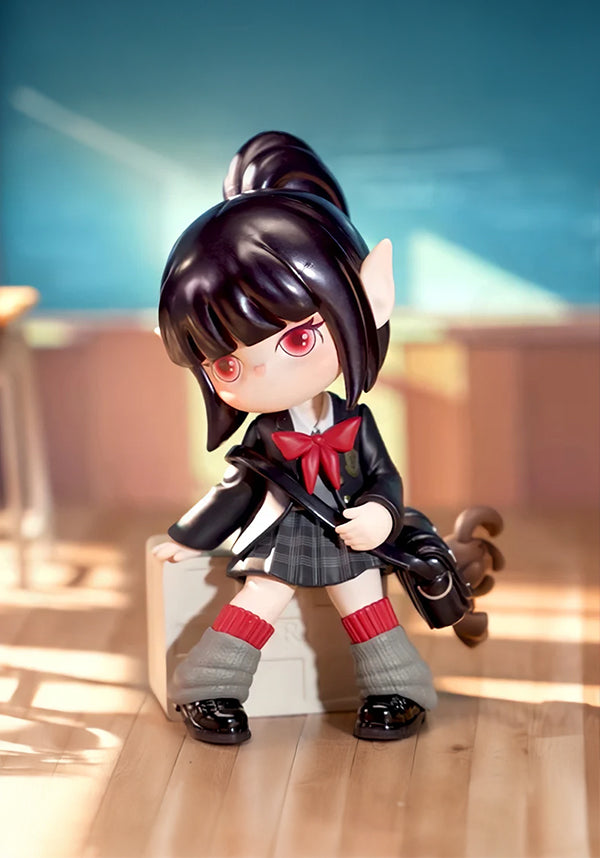 Toy figure of a character with black hair and red eyes, wearing a school uniform, standing on a wooden floor.