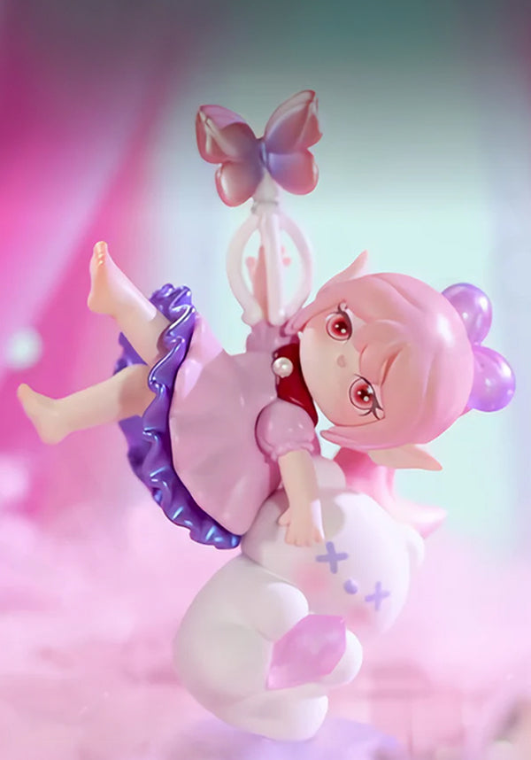 Toy figure of a fairy with pink hair and a butterfly on a colorful background