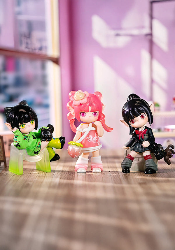 Three colorful figurines on a wooden surface with a blurred indoor background
