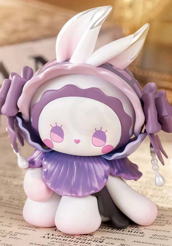 Cute figurine with purple hair and bunny ears on a textured surface