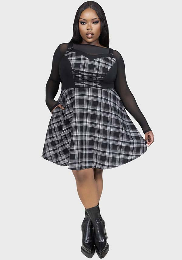 Plus size woman wearing a black and gray plaid dress with sheer sleeves on a white background