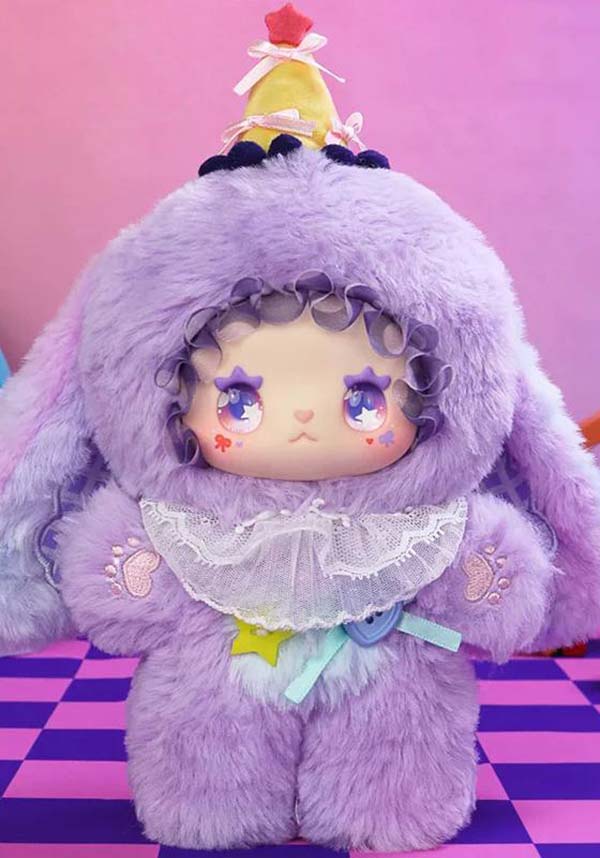 Cute plush toy with purple fur and a colorful hat on a pink and purple checkered floor.