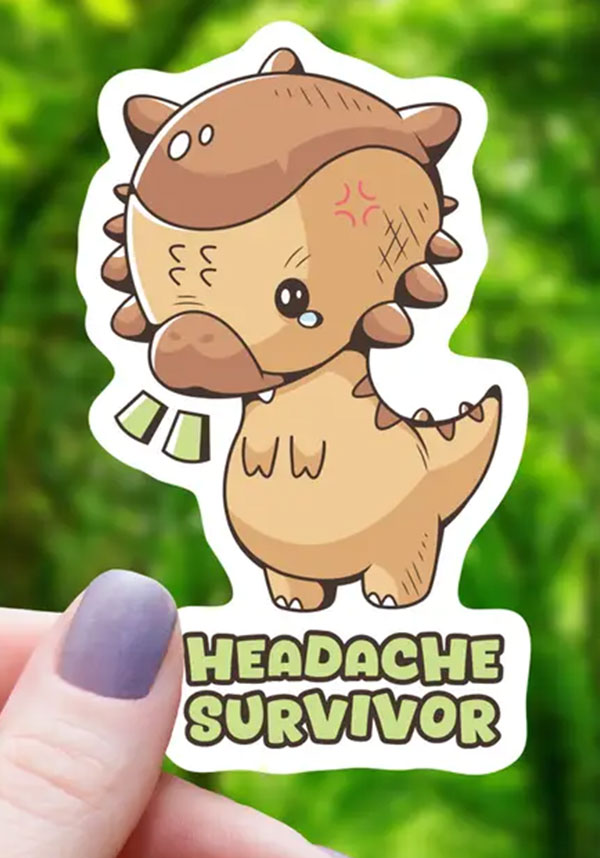 Sticker of a cartoon dinosaur with 'Headache Survivor' text held by a hand against a green blurred background